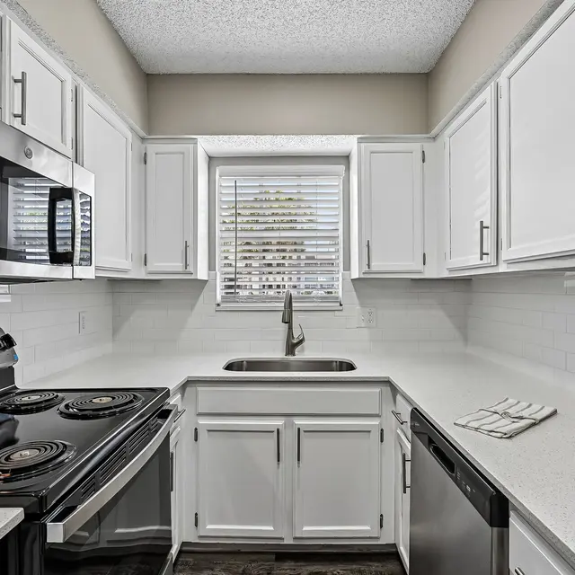 Modern Kitchen Interior A modern kitchen featuring white cabinets, stainless steel appliances, and a clean countertop with a sink and decorative vase.
