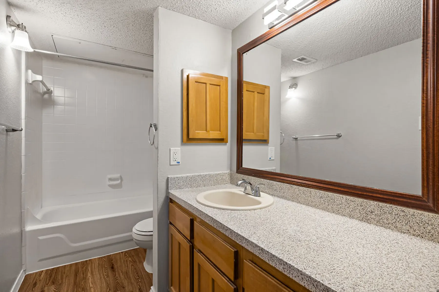 Modern Bathroom Design A modern bathroom featuring a bathtub, shower, and a vanity with a sink. The decor includes wooden cabinets and a large mirror above the sink.