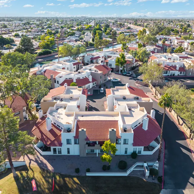 Aerial view of a residential neighborhood featuring multiple houses with red roofs and surrounding greenery.