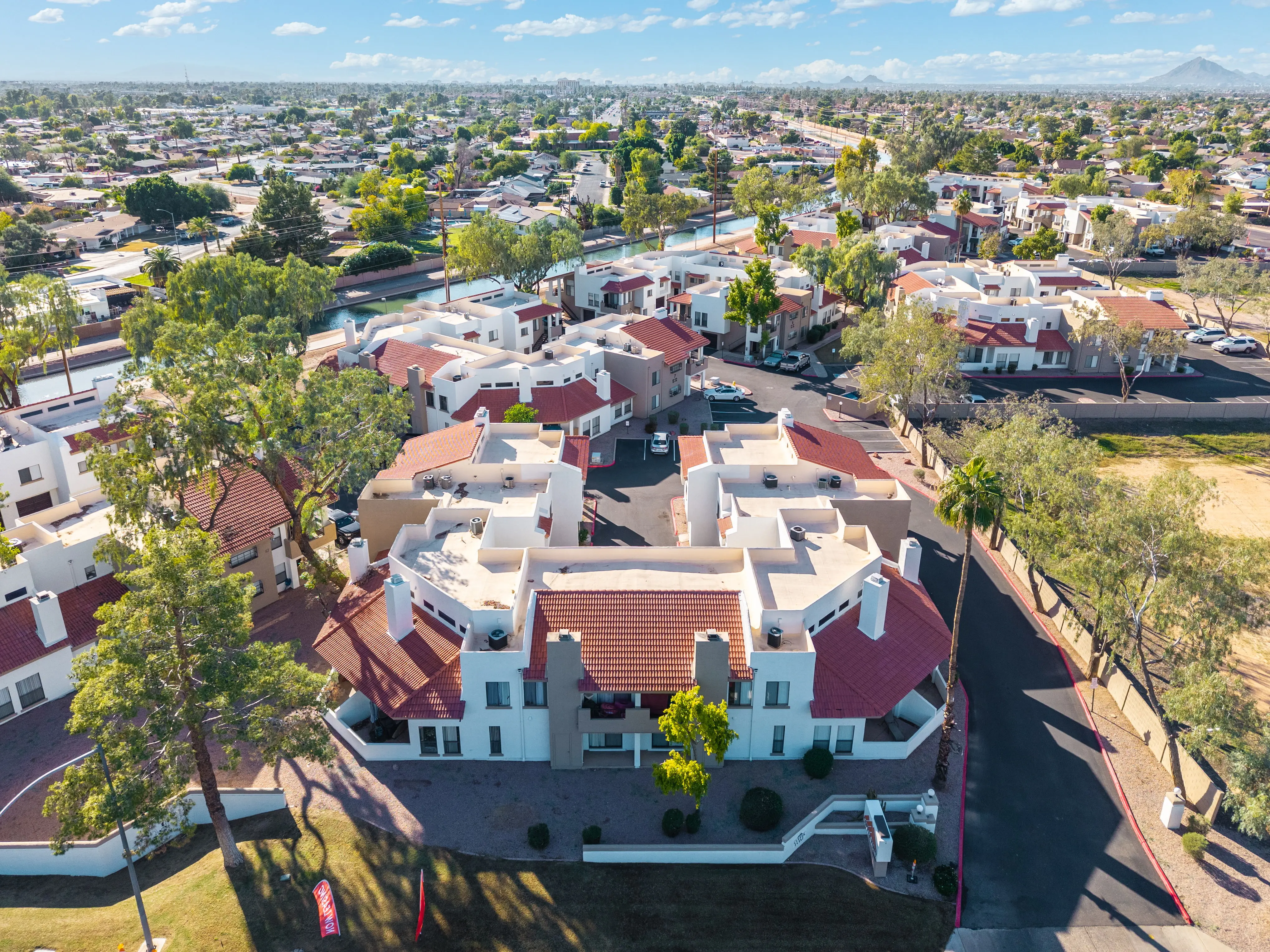 Aerial view of a residential neighborhood featuring multiple houses with red roofs and surrounding greenery.