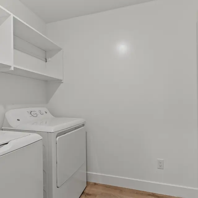 Bright and clean laundry room featuring a washing machine and dryer beside wall-mounted shelves.