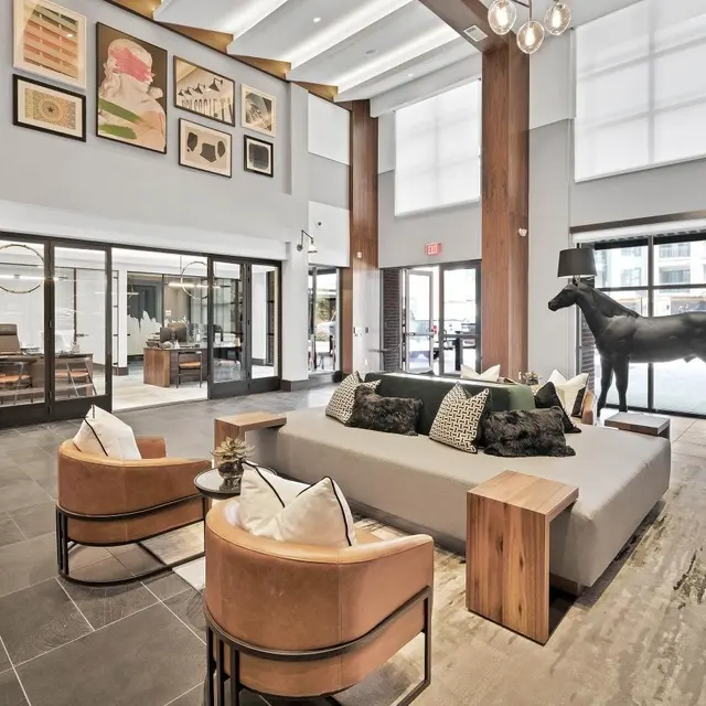 Modern Lobby Interior Design A modern lobby featuring a mix of contemporary and rustic design elements, with a gray couch, brown accent chairs, and a horse sculpture.