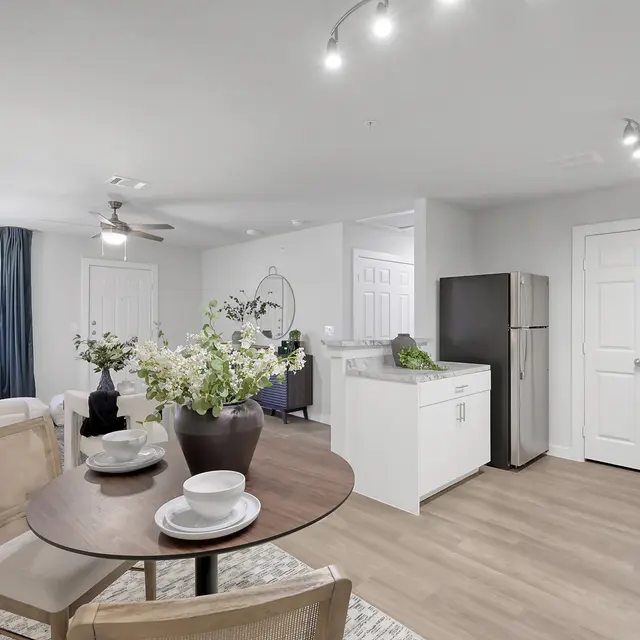 A modern apartment featuring a living space with a dining area, a kitchen with stainless steel appliances, and a cozy atmosphere.