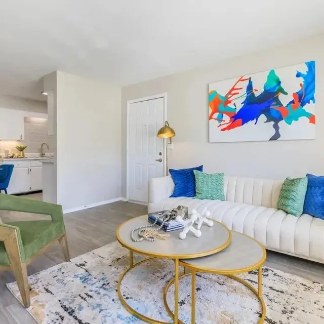 Bright living room featuring a white sofa with colorful pillows, a round coffee table, and modern decor.