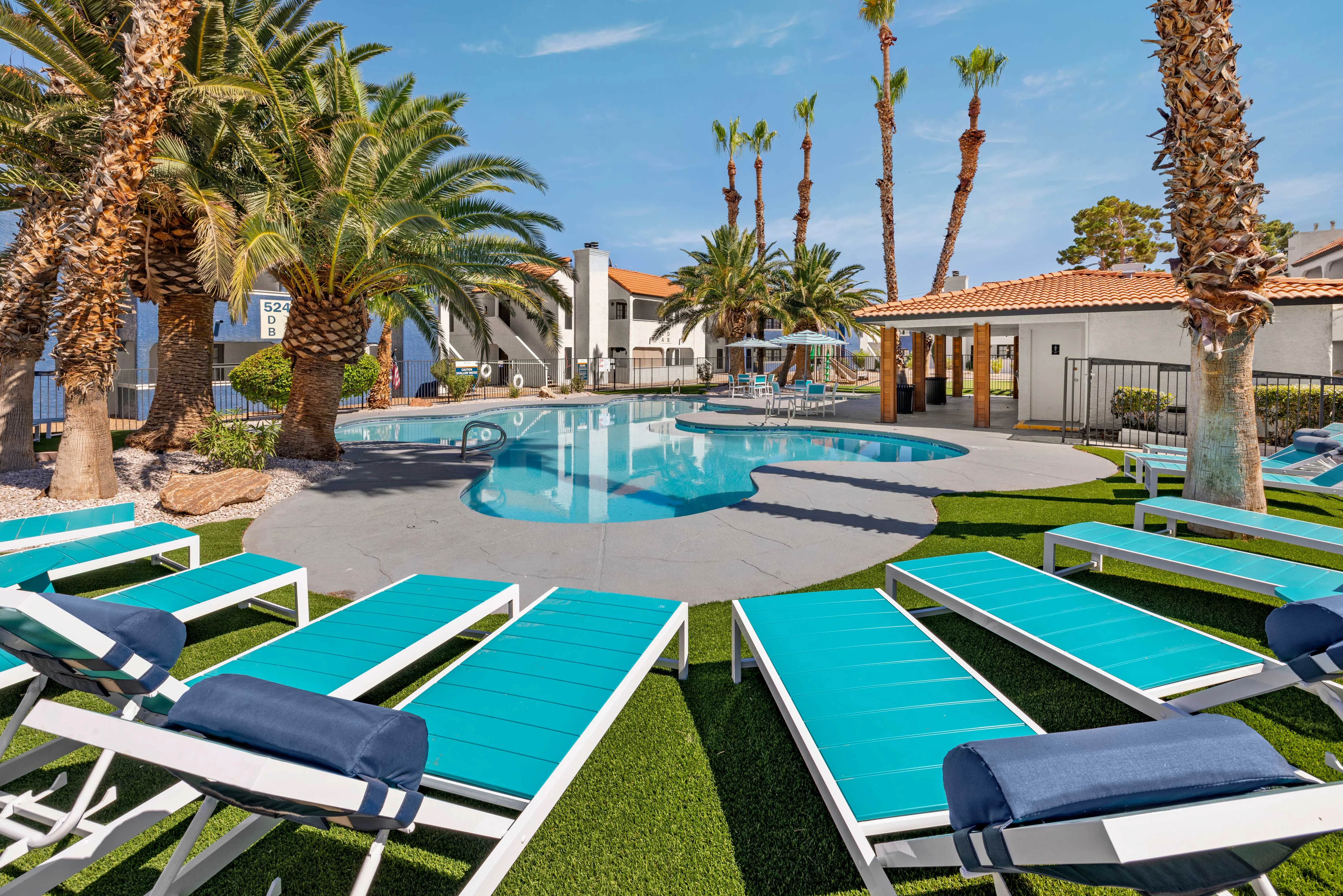 Inviting Swimming Pool Area A vibrant pool area surrounded by palm trees and lounge chairs on grass.