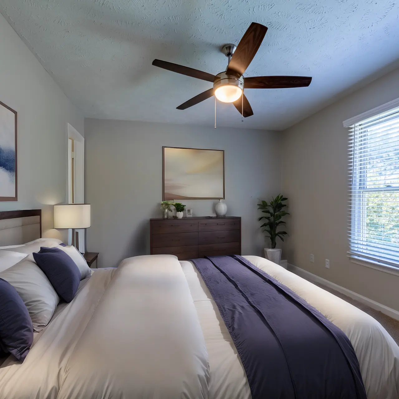 A modern and stylish bedroom featuring a king-size bed with navy blue and white bedding, a wooden nightstand with a lamp, and a minimalistic decor.