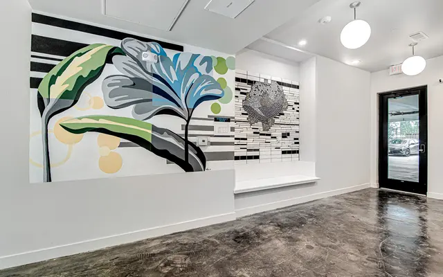 Interior space featuring a vibrant mural of green and blue leaves alongside a textured wall design with black and white tiles.