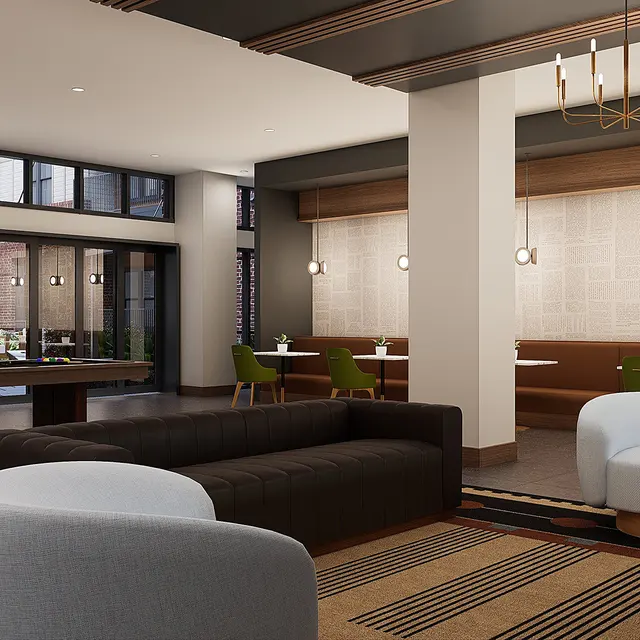 A spacious modern lobby featuring a brown sofa, white accent chairs, a large table, and decorative lighting.