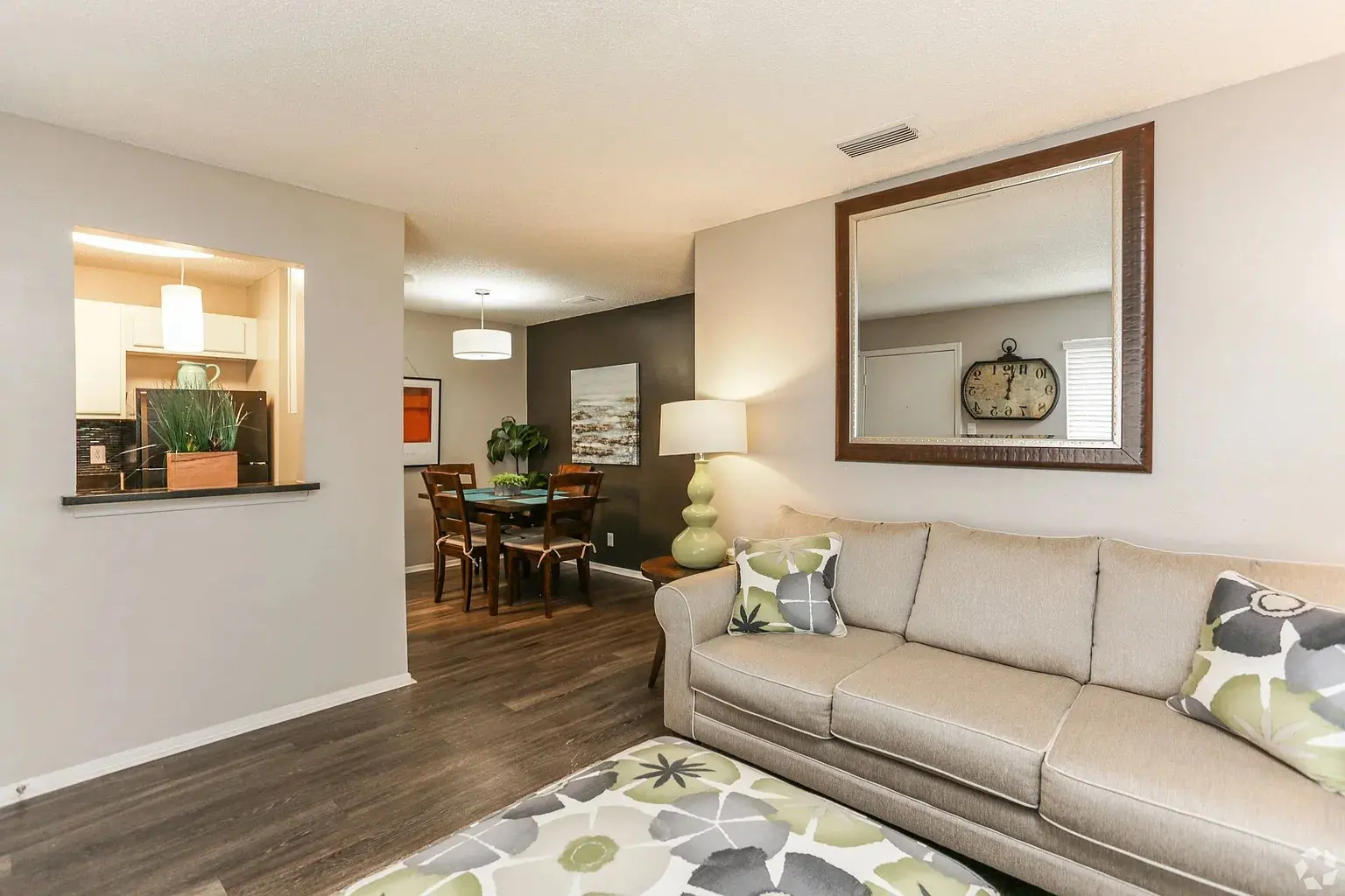 Stylish Living Space A cozy living room with a couch and a dining area visible in the background. The living room features a neutral color palette with decorative pillows and a coffee table. The dining area is set up with a wooden table and chairs.