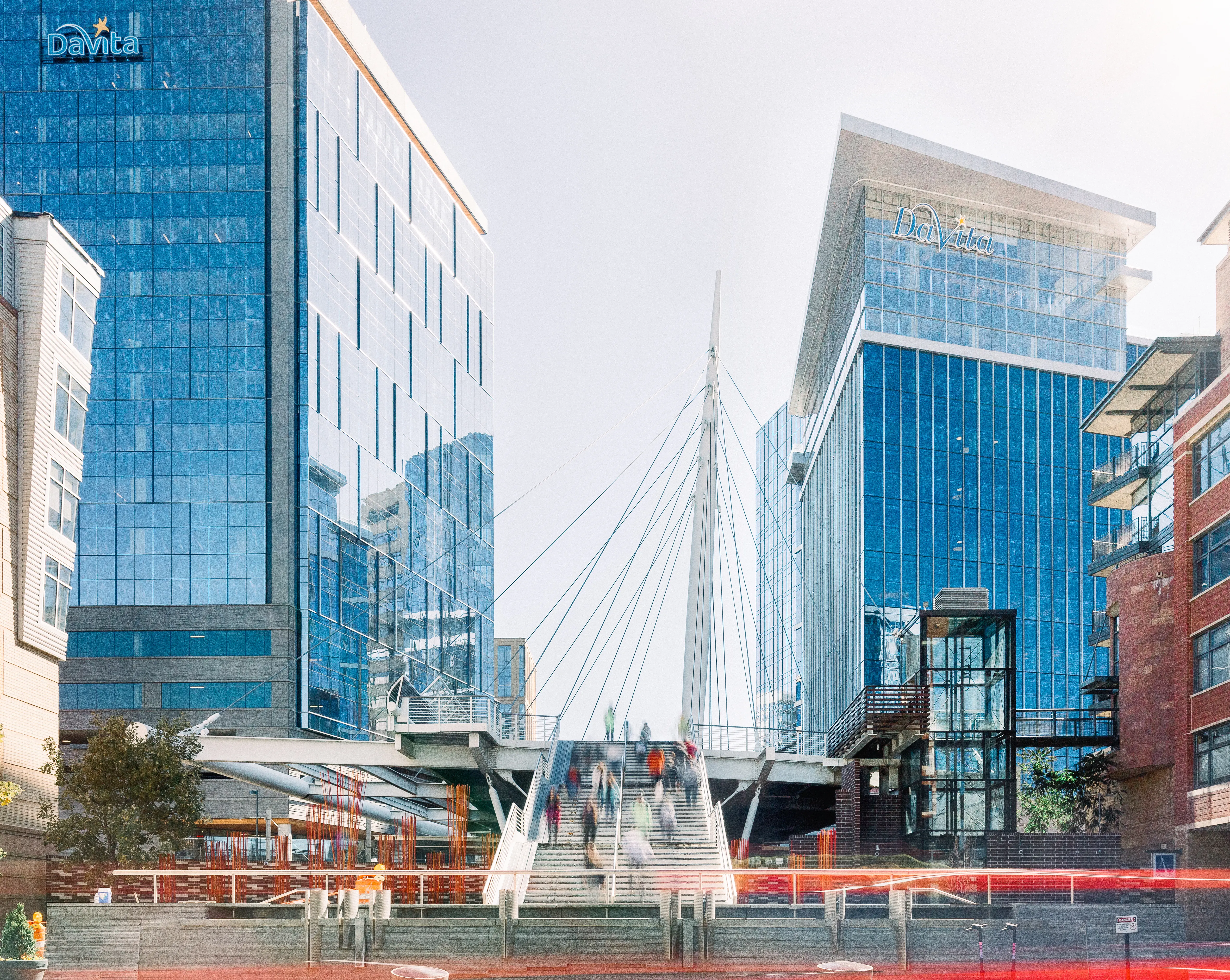 A modern urban landscape featuring two tall glass buildings connected by a pedestrian bridge.