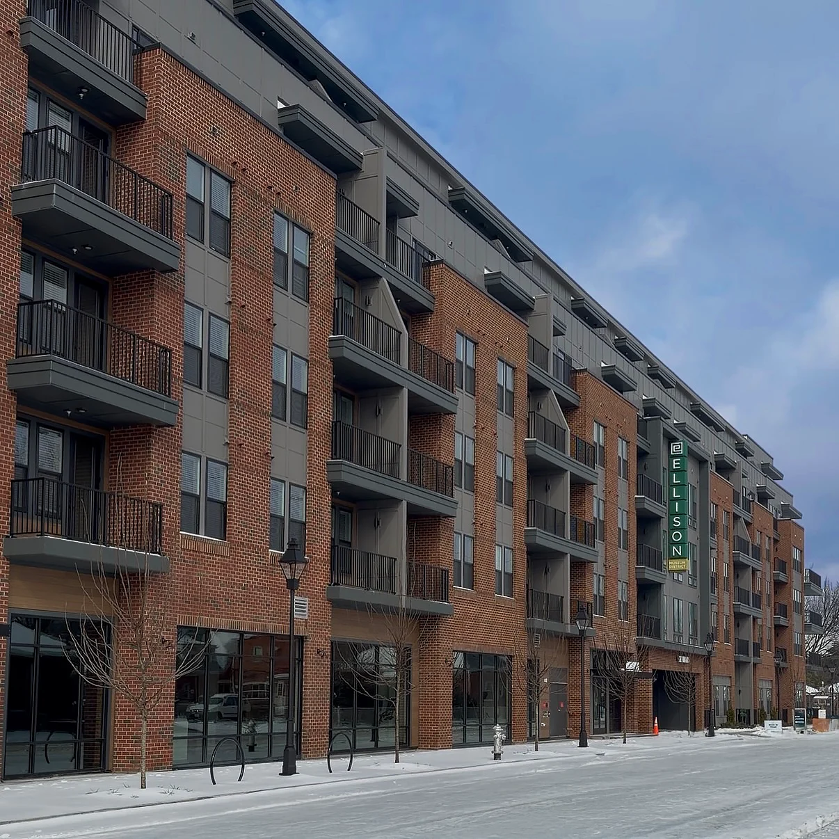 The Ellison Apartment Building Exterior view of The Ellison apartment building featuring a brick façade and large windows with balconies.