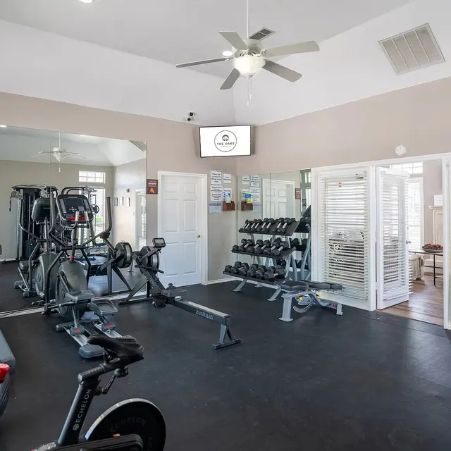 Interior view of a gym featuring exercise equipment and a mirrored wall.