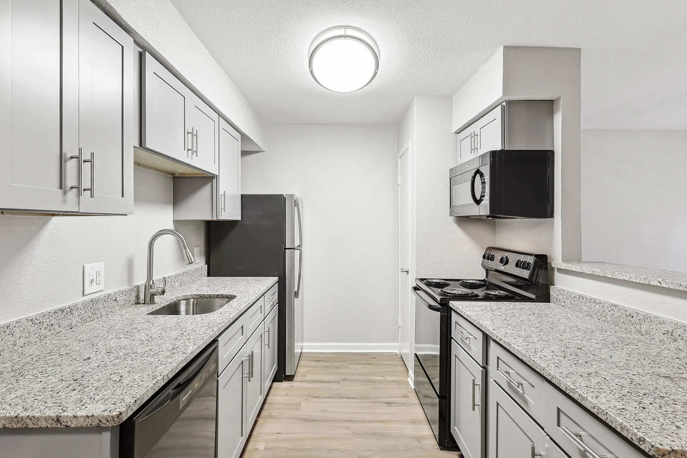 A modern kitchen featuring gray cabinets, stainless steel appliances, and granite countertops with a focus on clean lines and a bright atmosphere.
