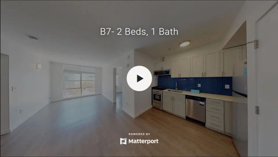 A spacious living area featuring an open kitchen with modern appliances, two windows providing natural light, and a comfortable atmosphere.