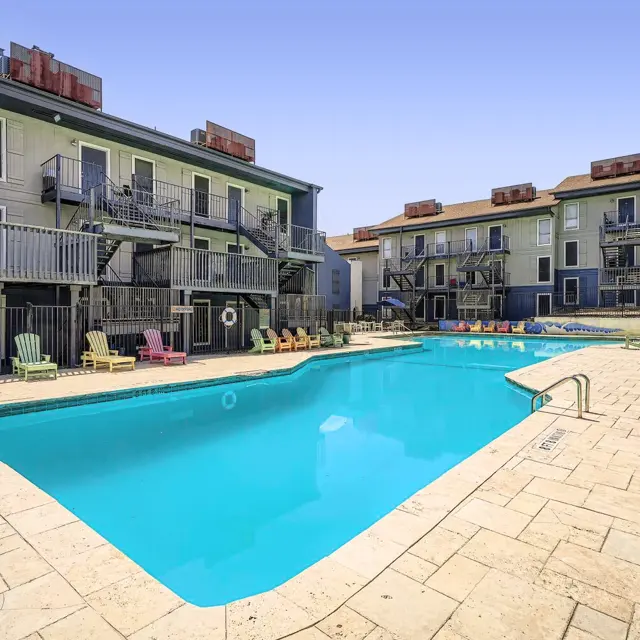 Relaxing Apartment Complex Pool Area An inviting apartment complex swimming pool area with lounge chairs and a clear blue sky.