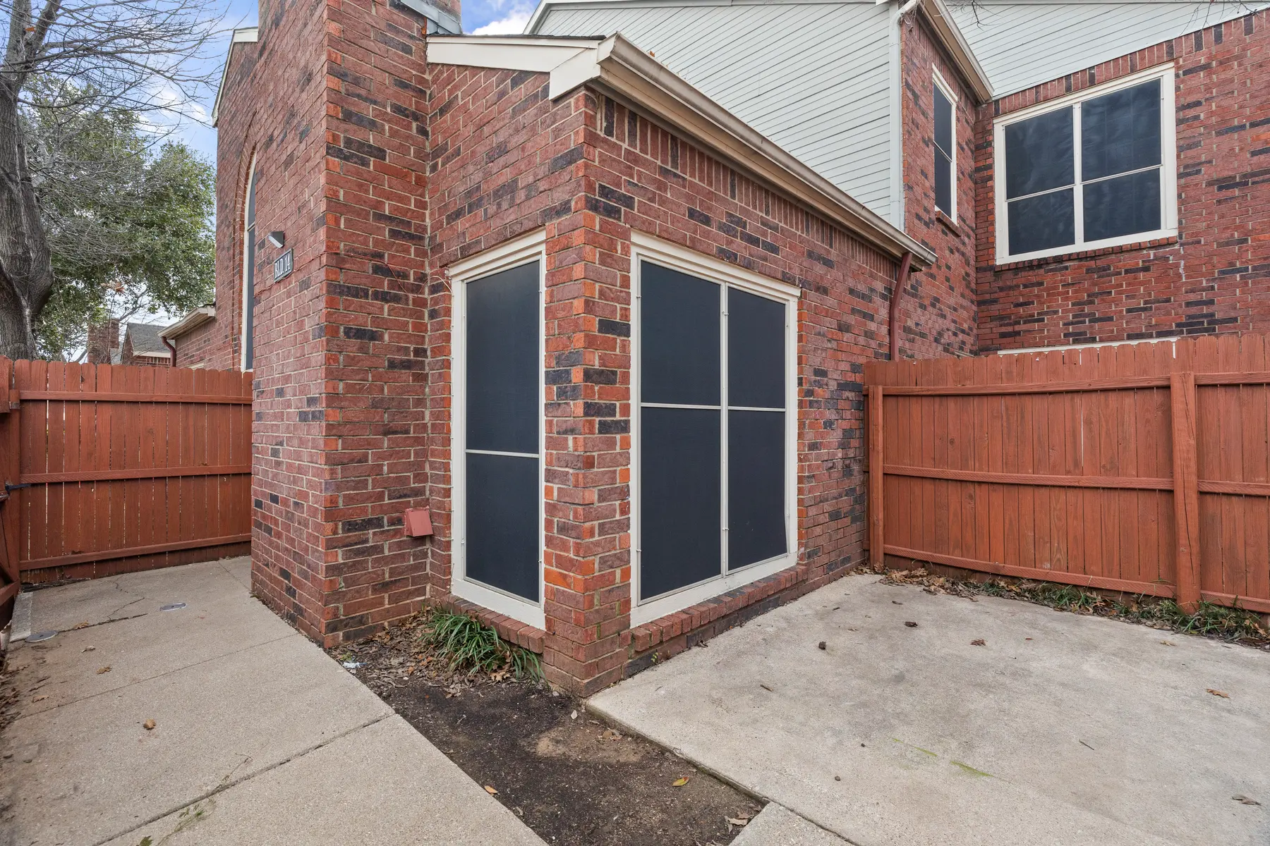 Exterior view of a brick building corner with a fenced yard