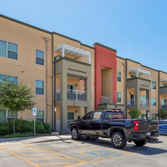 Exterior view of a modern apartment complex with a truck parked in front.