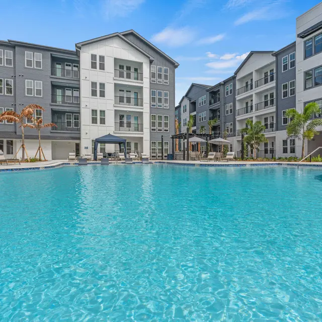 Luxury Apartment Pool Area A serene pool area surrounded by modern apartment buildings. The water is clear and inviting, with lounge chairs and cabanas present around the pool.