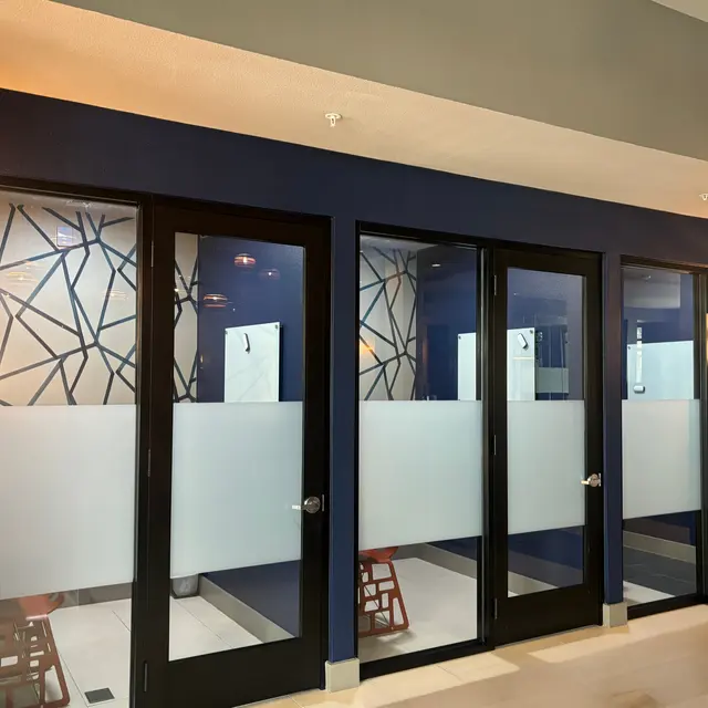 A modern design of a restroom façade with frosted glass doors and geometric patterns in the background.