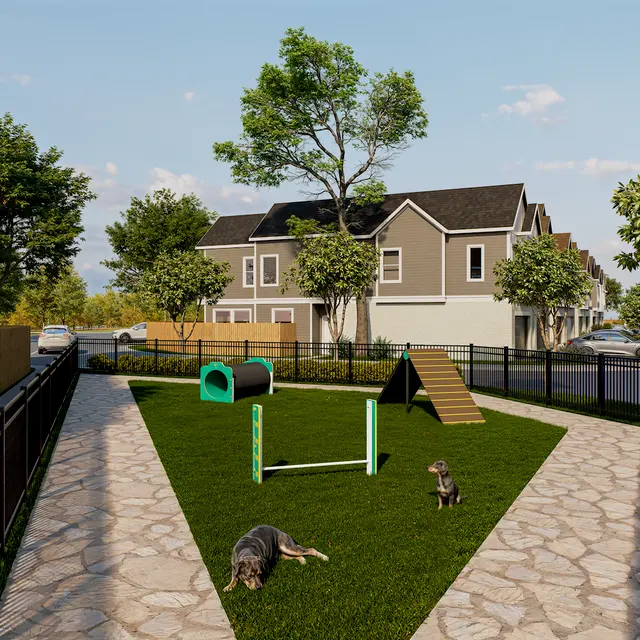 Dog Park Area A dog park with green grass, agility equipment, and trees. Two dogs are visible: one lounging on the grass and the other near agility equipment. Residential buildings are in the background.