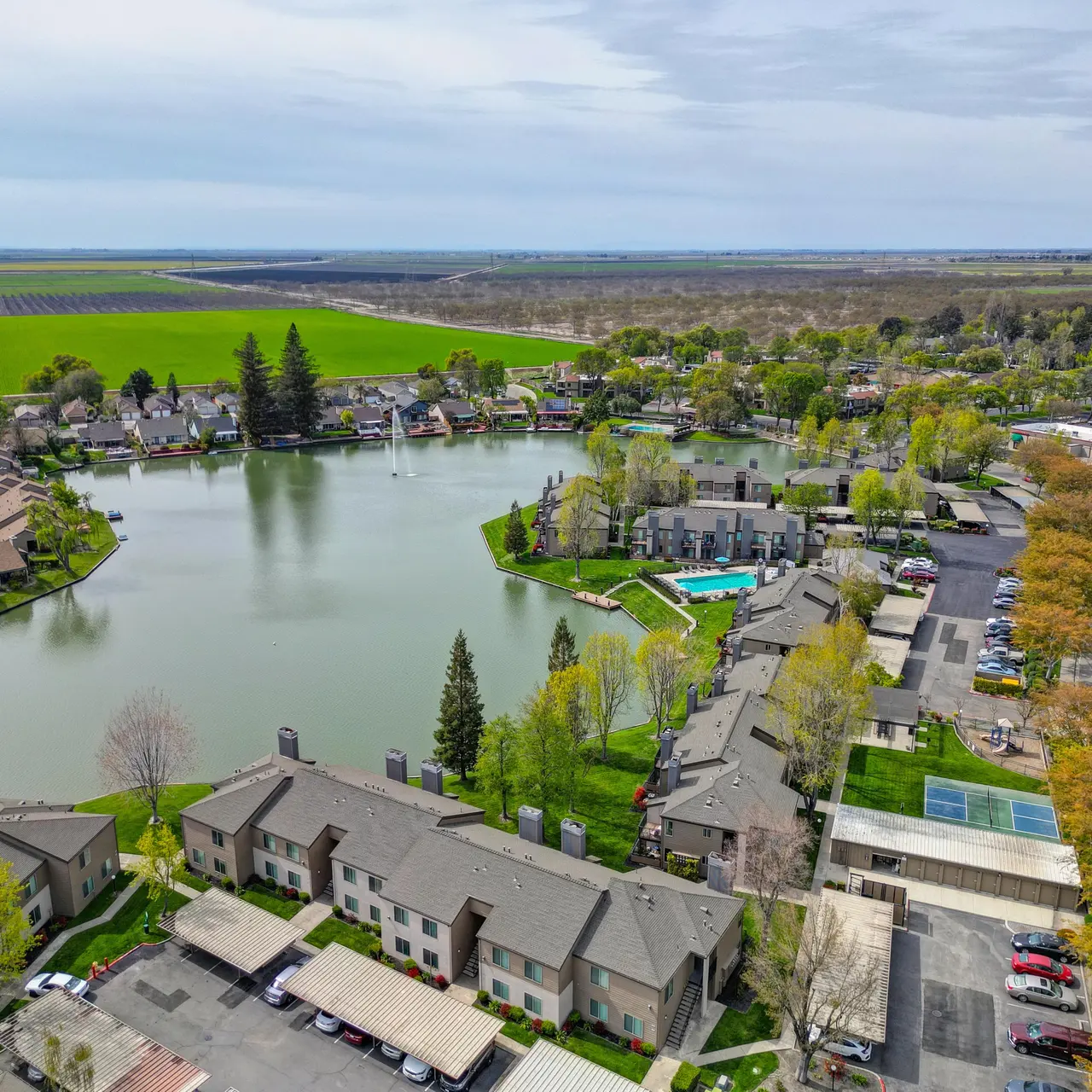 Aerial view of a lakeside community featuring a large lake surrounded by residential buildings and greenery.