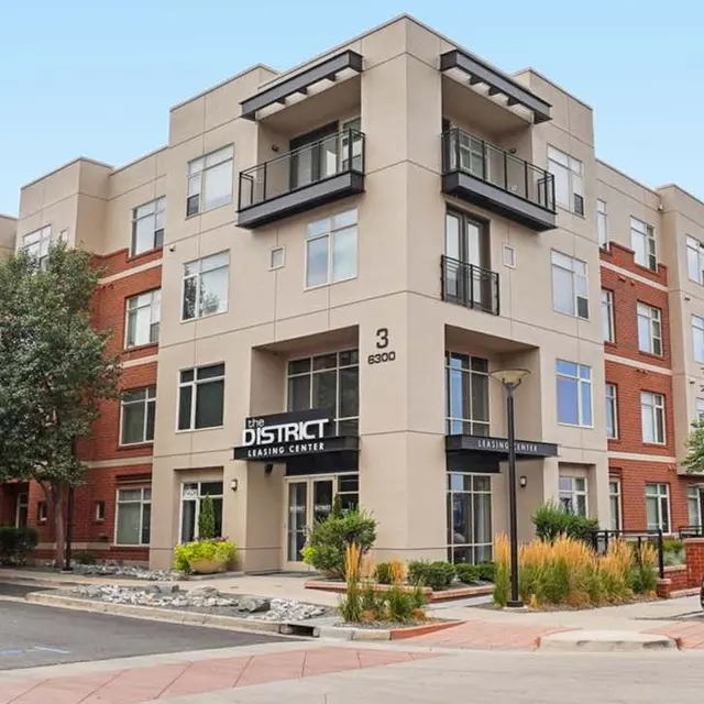 Exterior view of the District Apartment Center building featuring a contemporary design with balconies and landscaping.