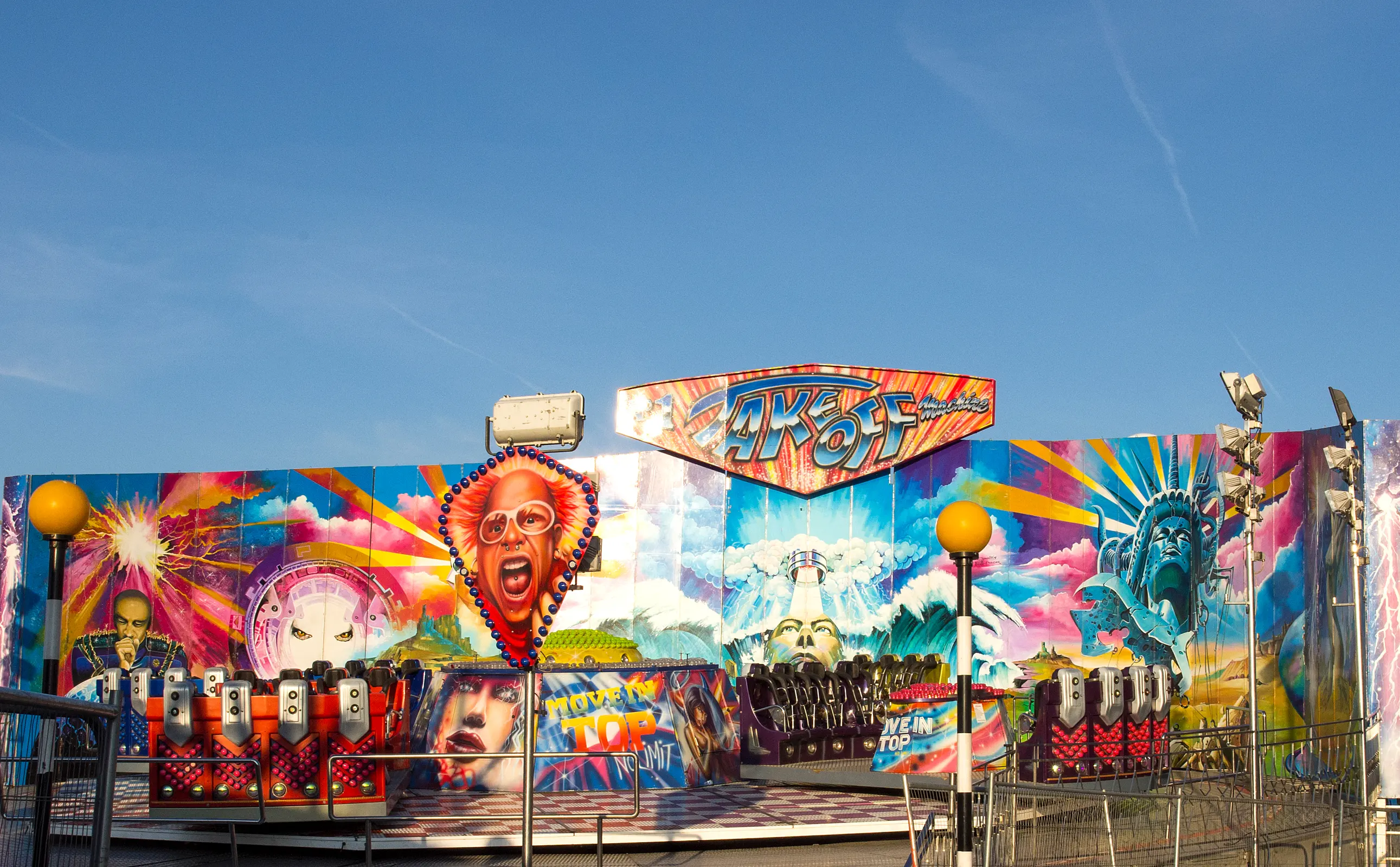 Vibrantly decorated amusement ride with colorful murals and designs, featuring a face with sunglasses and iconic landmarks.