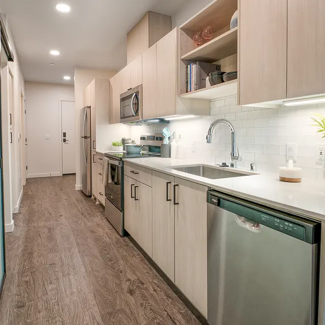 A modern kitchen with wooden cabinets, stainless steel appliances, and a minimalist design.