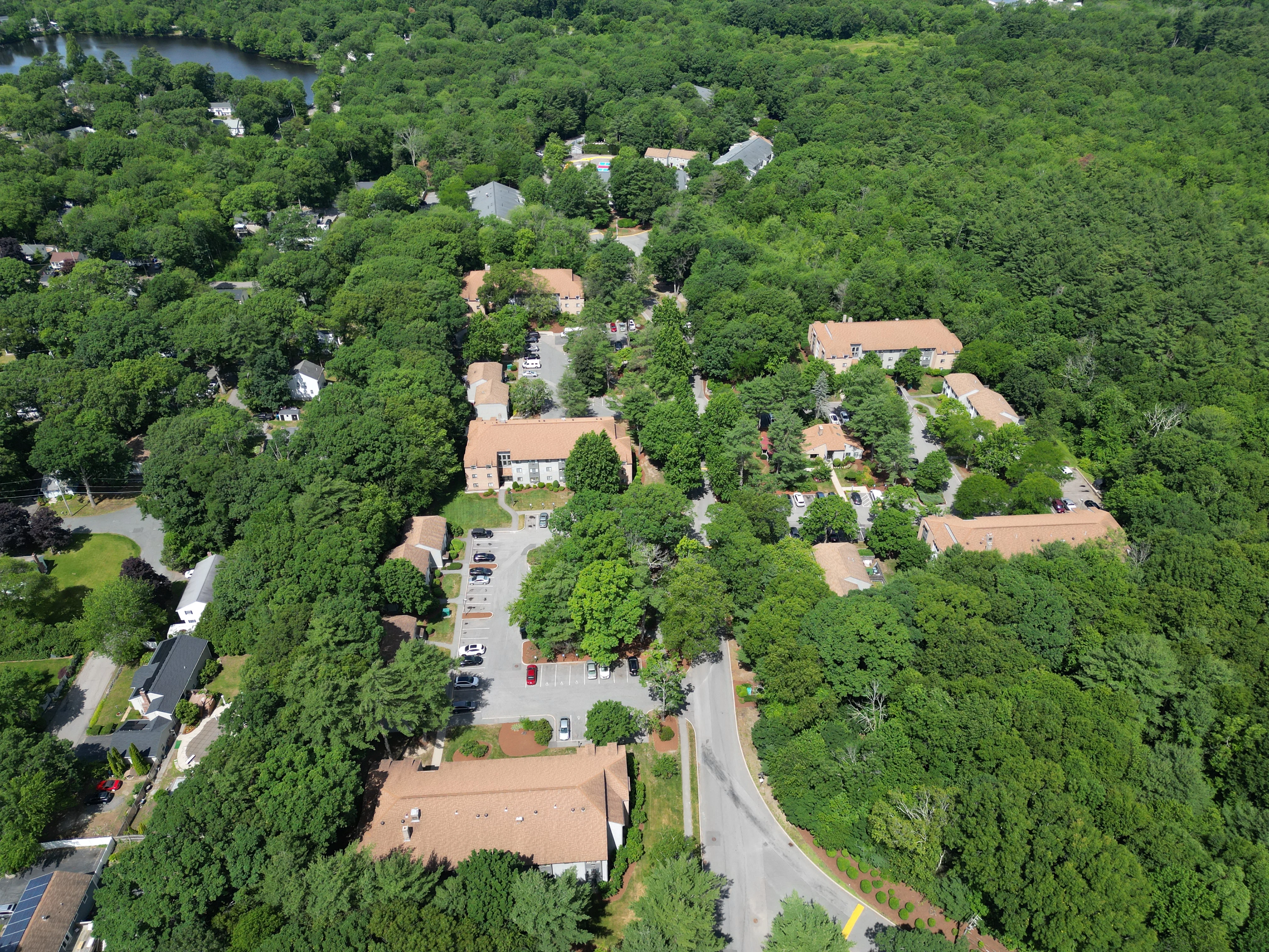 Aerial View of Ramblewood Apartments in Holbrook MA Aerial view of Ramblewood Apartments in Holbrook, Massachusetts featuring apartment homes, mature trees, parking areas, and community grounds.
