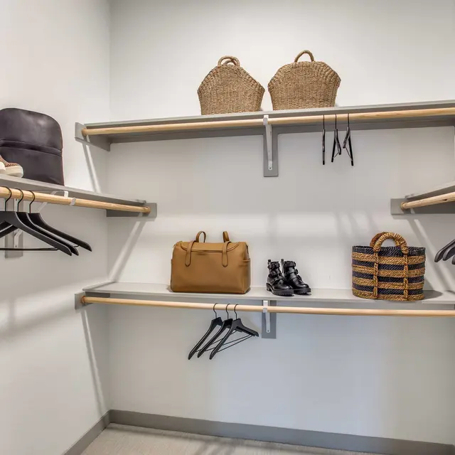 An organized closet space with shelves containing bags, shoes, and decorative boxes.