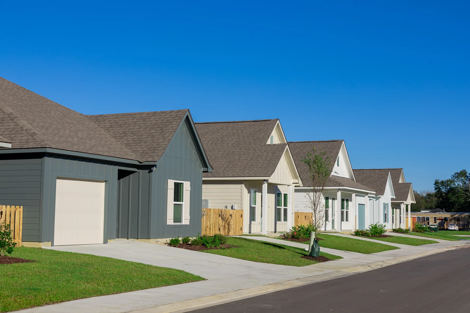 Row of newly constructed houses with different colors and styles on a clear day.