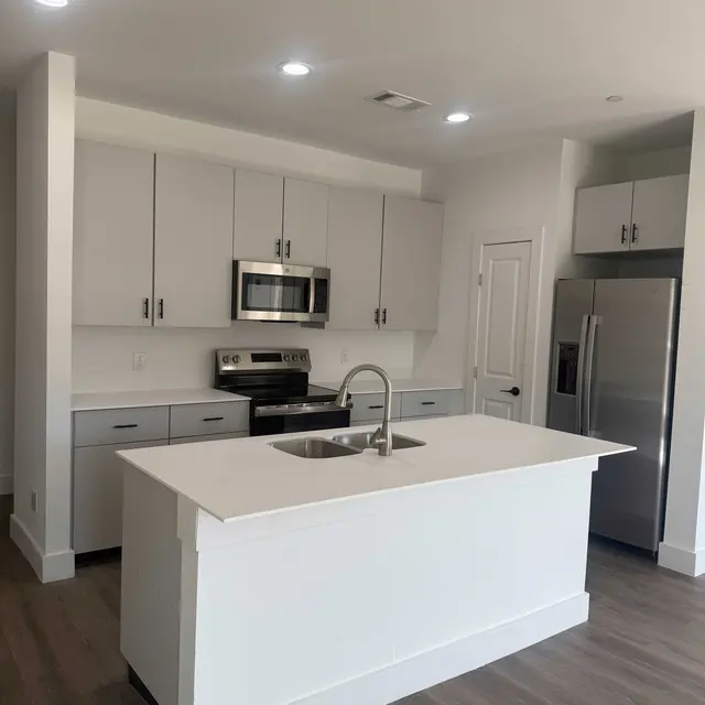 A modern kitchen featuring a central island, stainless steel appliances, and light-colored cabinetry.