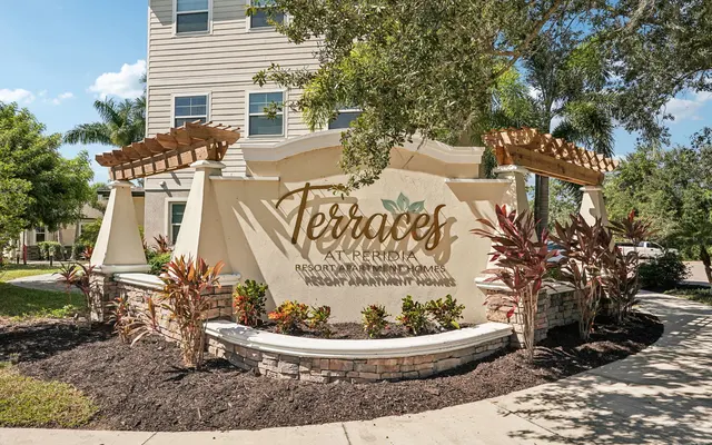 Welcome to Terraces at Perdido A decorative sign for 'Terraces at Perdido' featuring landscaping with plants and trees.