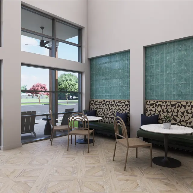 A modern cafe interior featuring large windows, natural light, and a mix of seating options. There are tables and chairs, as well as a cozy banquette with decorative wall panels. The flooring is light wood in a herringbone pattern.