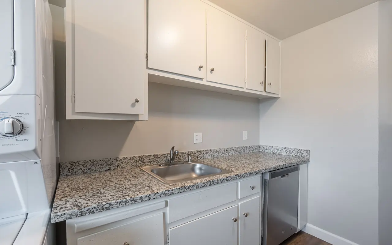 A modern kitchen with white cabinets and granite countertops.
