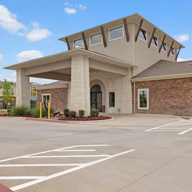 Modern Architectural Design Modern building with a distinctive roof and a stone facade, featuring a welcoming entrance and a paved parking area.