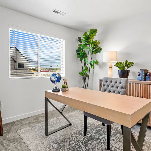A modern office space featuring a wooden desk, a comfortable chair, and decorative elements like a globe and a plant. Natural light enters through a window, illuminating the room.