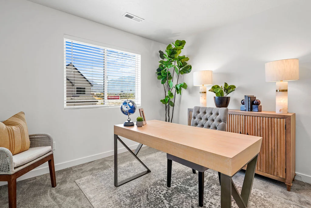 A modern office space featuring a wooden desk, a comfortable chair, and decorative elements like a globe and a plant. Natural light enters through a window, illuminating the room.