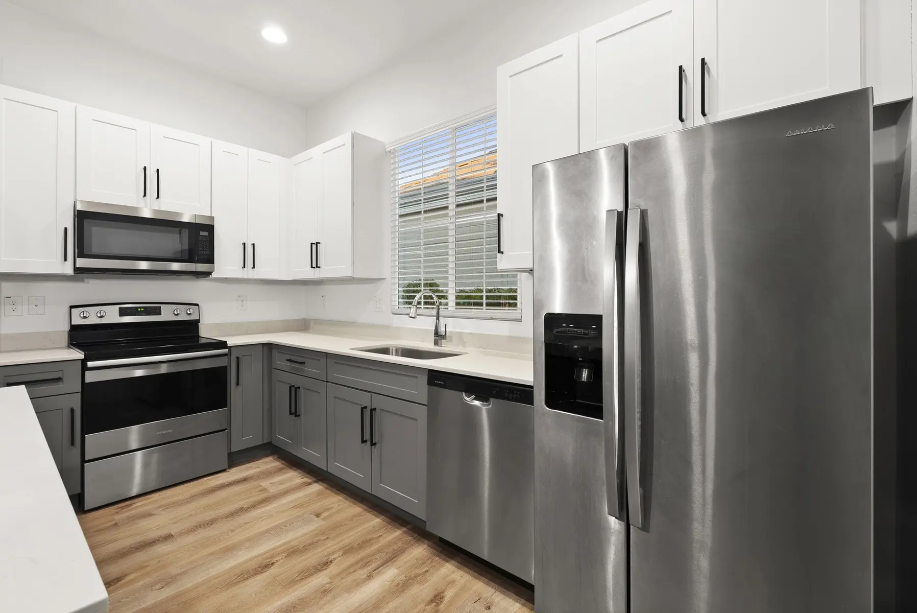 Modern kitchen with stainless steel appliances, white cabinets, and light wood flooring. Bright and spacious with natural light.