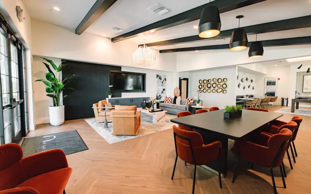 A stylish modern living space featuring comfortable seating, a large dining table, and a decorative atmosphere with plants and wall art.