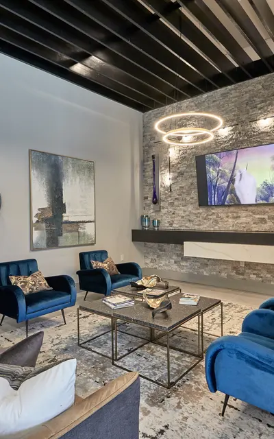 A modern living room featuring a combination of beige and blue seating, decorative wall plates, a television mounted on a stone feature wall, and stylish decor elements.