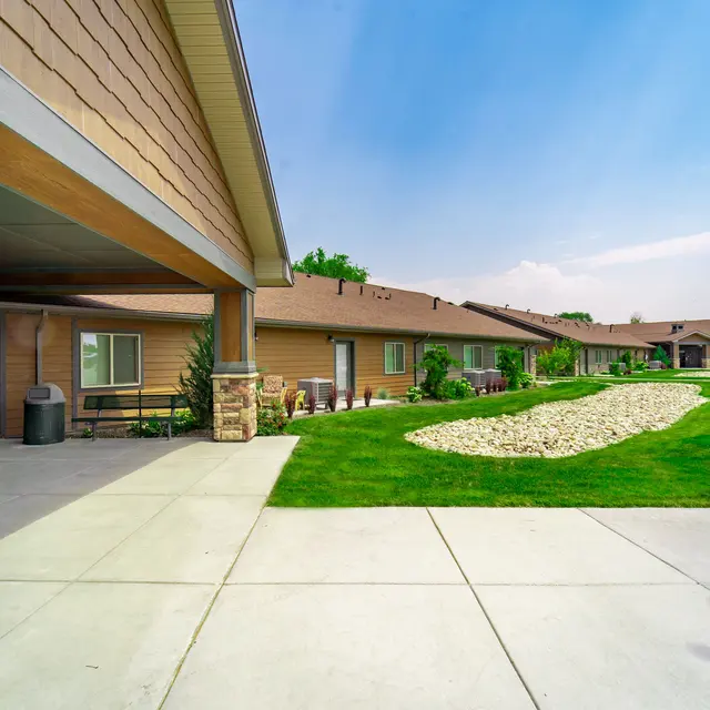 Apartment Complex Exterior A view of an apartment complex with a landscaped area and a clear blue sky.