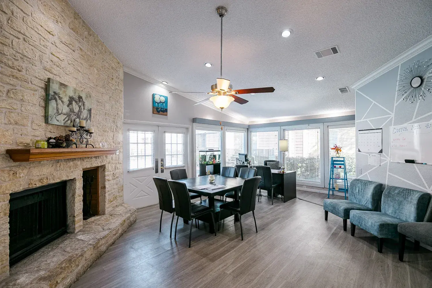 Cozy Modern Living Room A spacious, airy living room featuring a stone fireplace, a wooden dining table with chairs, and large windows letting in natural light.