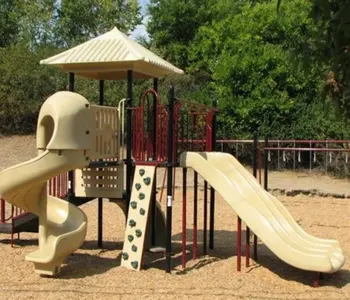A playground structure featuring a beige slide and climbing equipment under a roof.