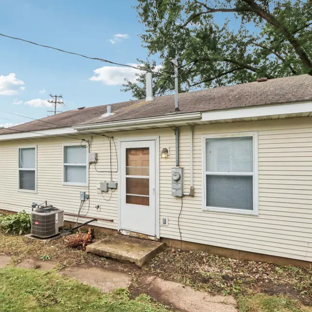 Side view of a single-story house with beige siding and a small front porch.