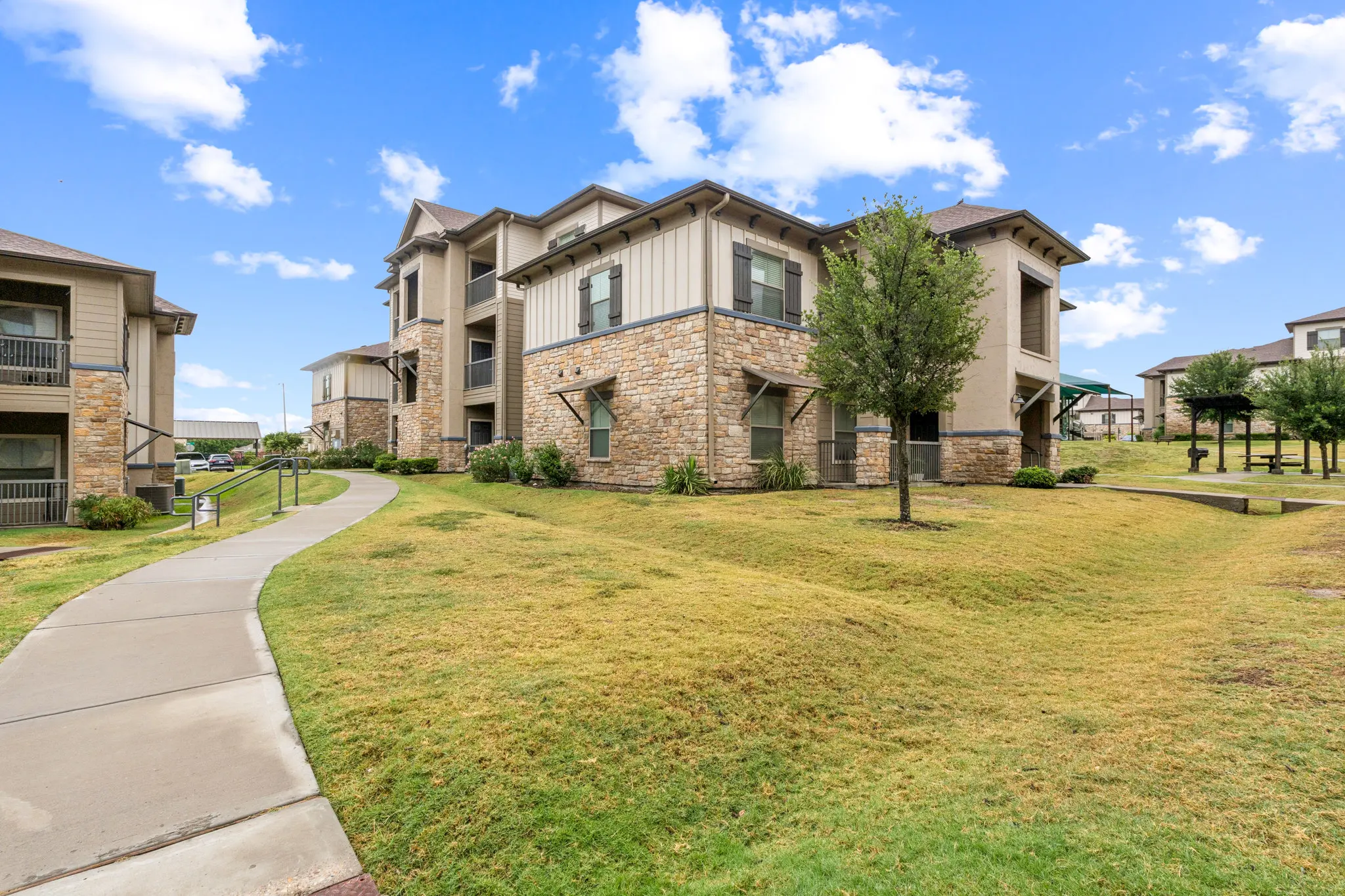 Exterior view of an apartment complex with grassy area and walking path