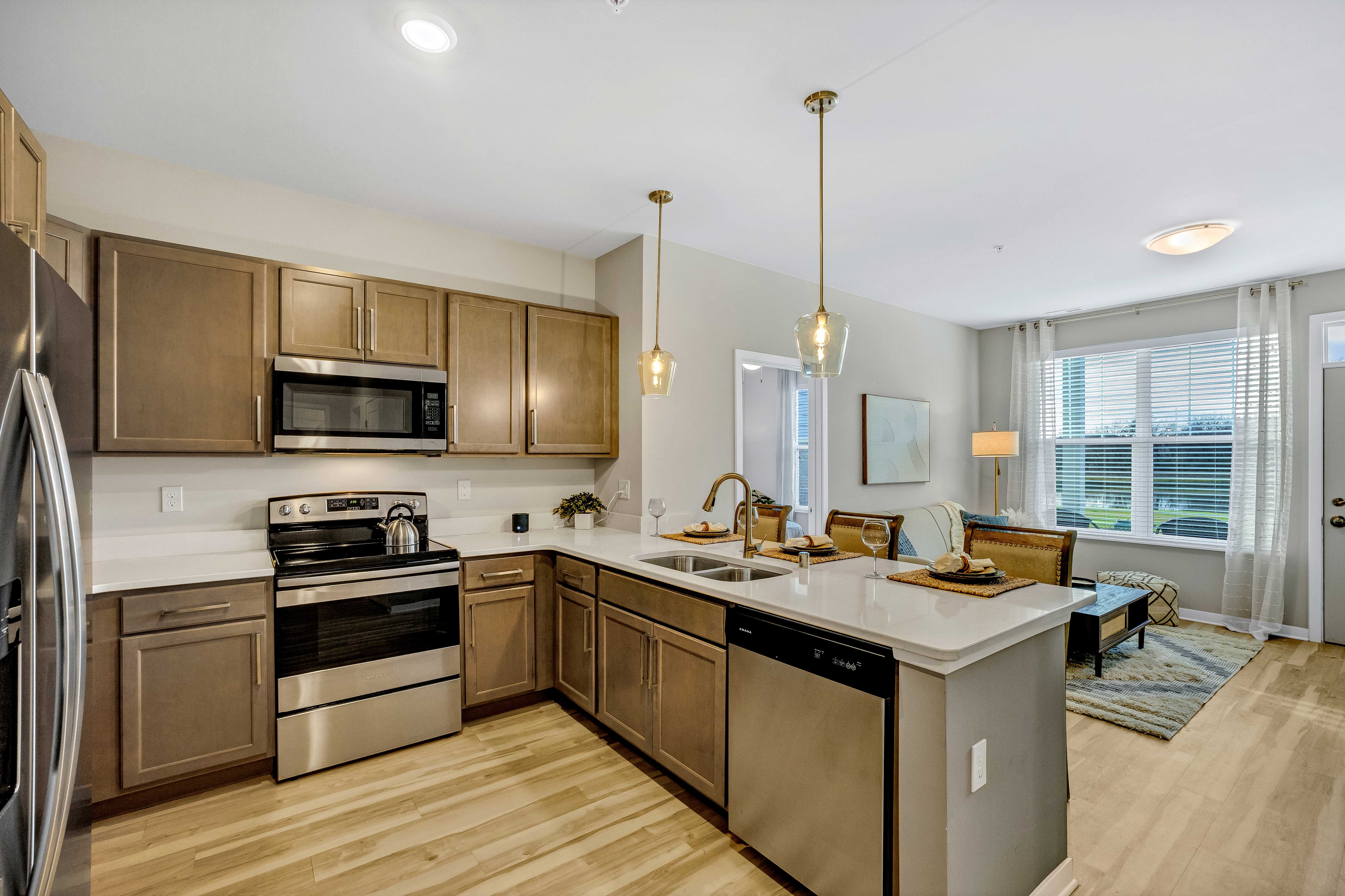 Stylish Modern Kitchen A modern kitchen featuring stainless steel appliances, wooden cabinets, and an island with a sink. The kitchen opens to a bright living area with a seating arrangement.