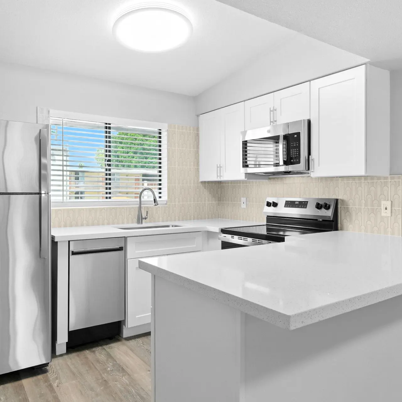 Contemporary Kitchen Interior A modern kitchen featuring stainless steel appliances, a white countertop, and a window with blinds.