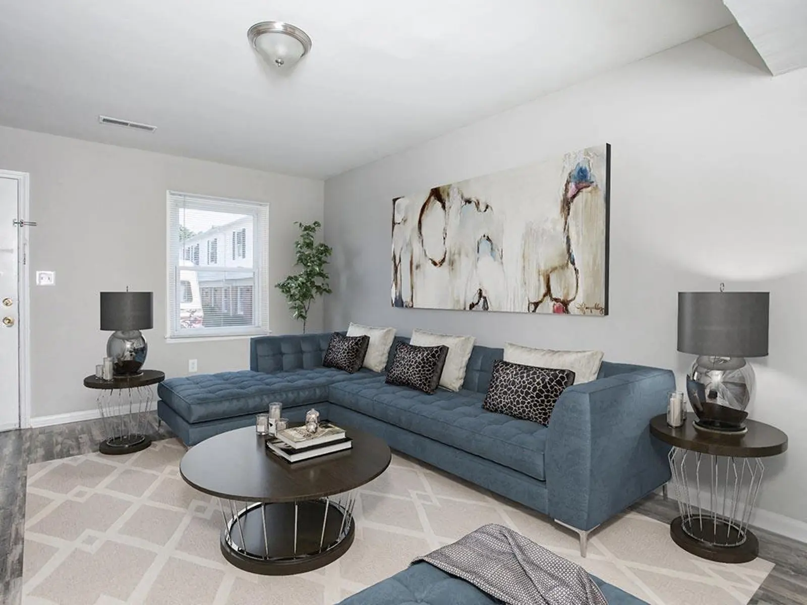 A stylish living room featuring a blue sectional sofa, round coffee table, and decorative artwork on the wall.