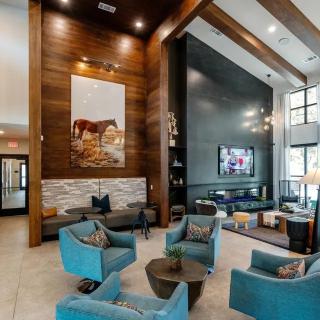 Spacious and stylish lobby area featuring bright turquoise seating, wooden beams, and large windows with natural light.